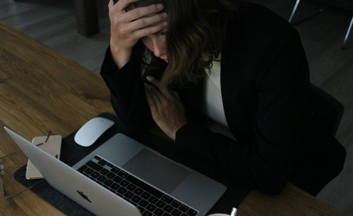 stressed woman with head in hands at laptop