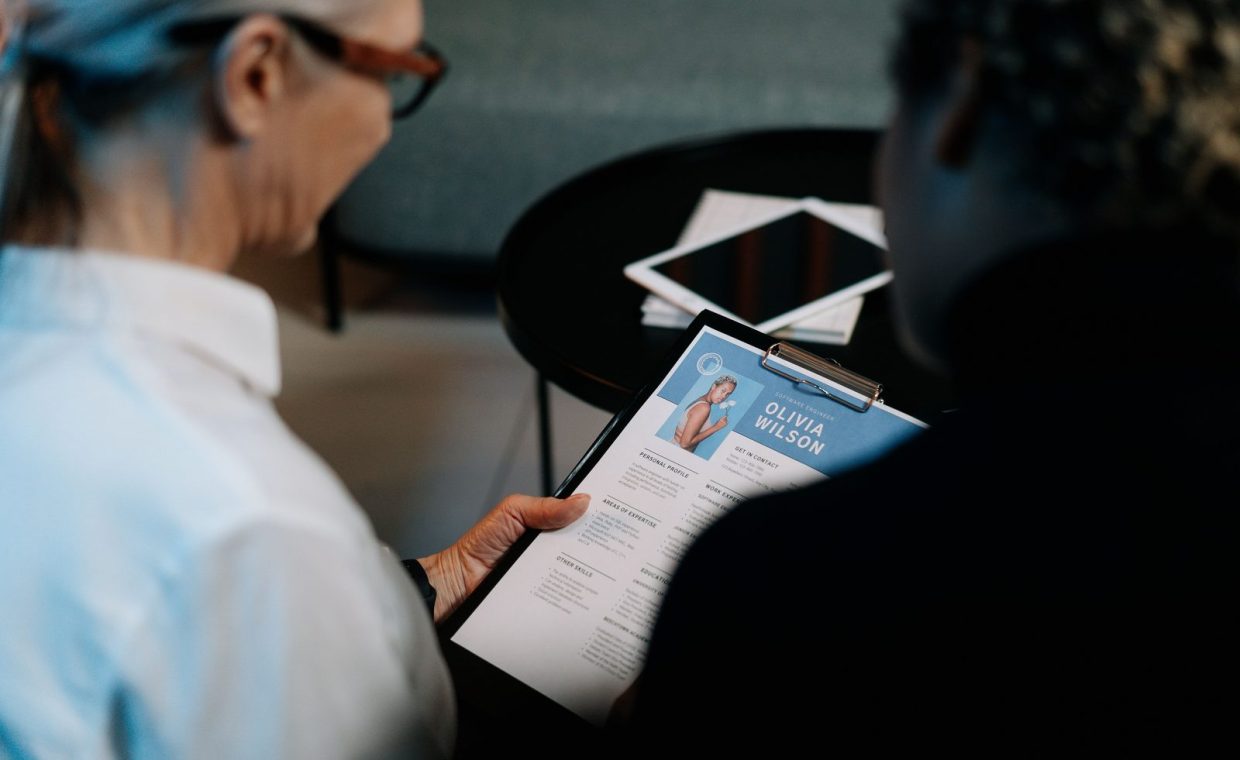 Business professionals conducting an interview with resume on clipboard in an office setting.