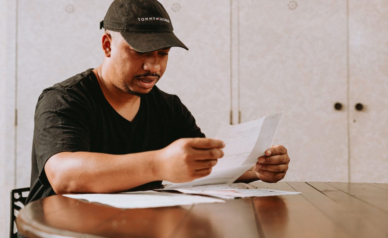 Adult man sitting at home table, focused on reviewing important documents.