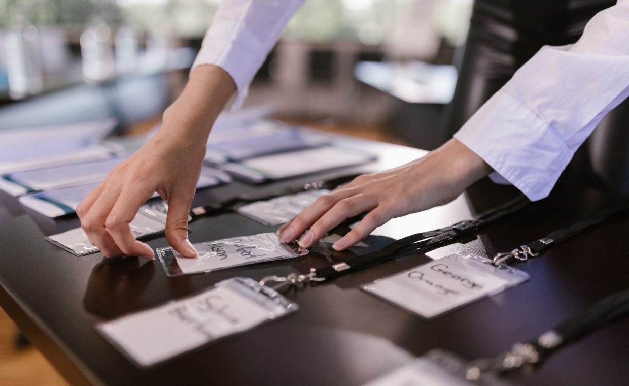 Close-up of hands arranging name tags on a conference table, preparing for a corporate event.