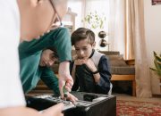Three children collaborating to repair a computer, using tools indoors.