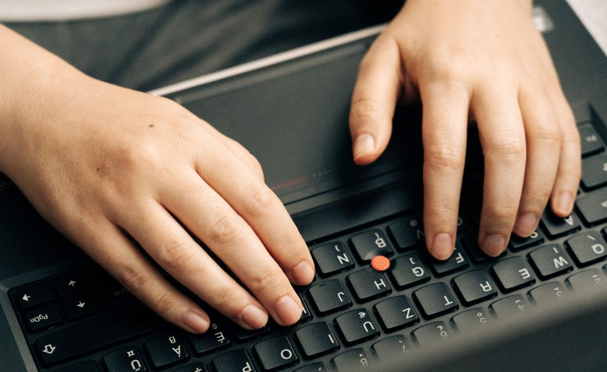 Close-up of hands typing on a black laptop's keyboard emphasizing productivity.