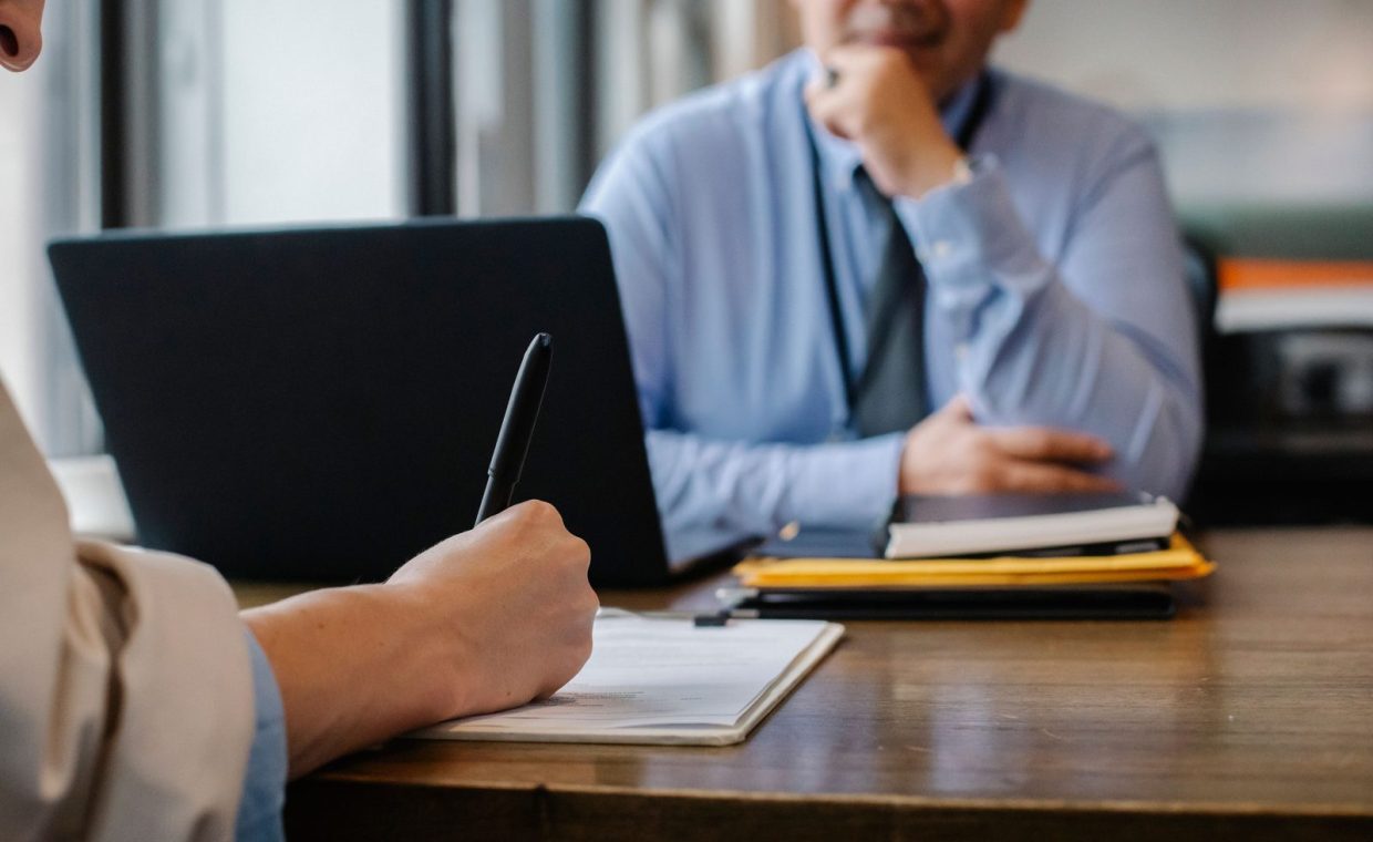 Crop anonymous female filling questionnaire when applying for job sitting in employer office