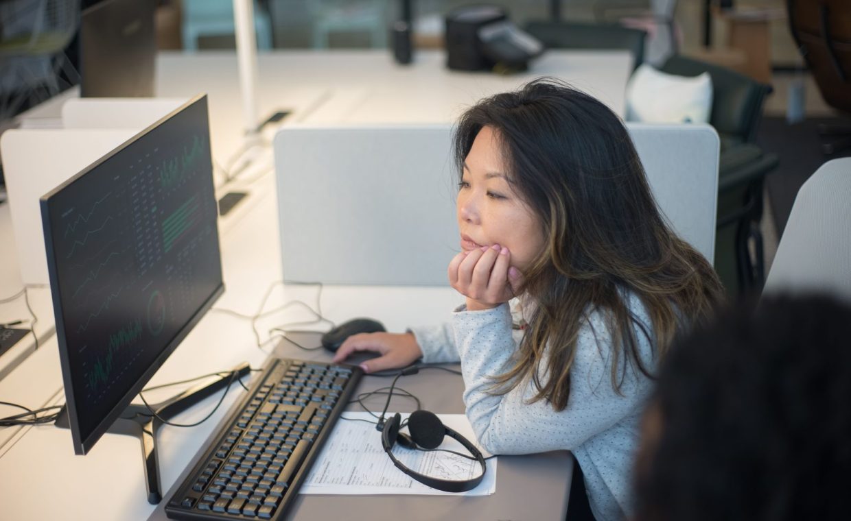 Woman intently viewing a computer monitor in a modern office environment.