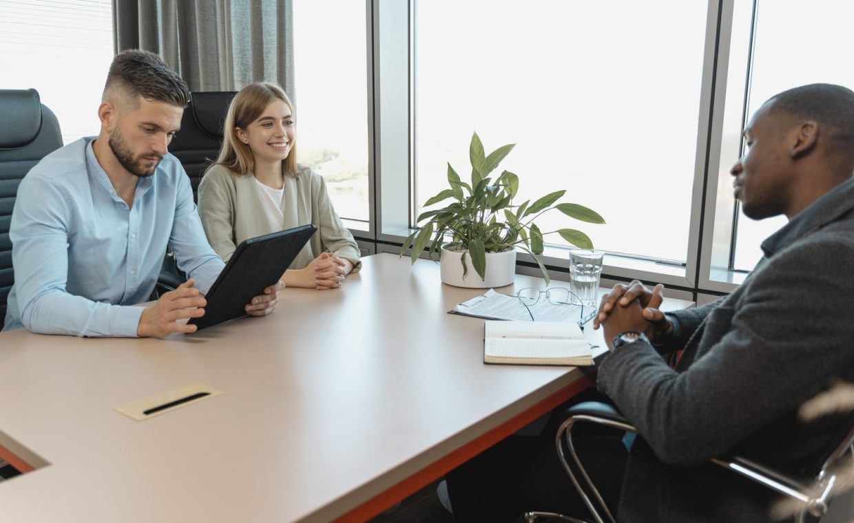 A business interview with three people in a modern office room, highlighting collaboration.