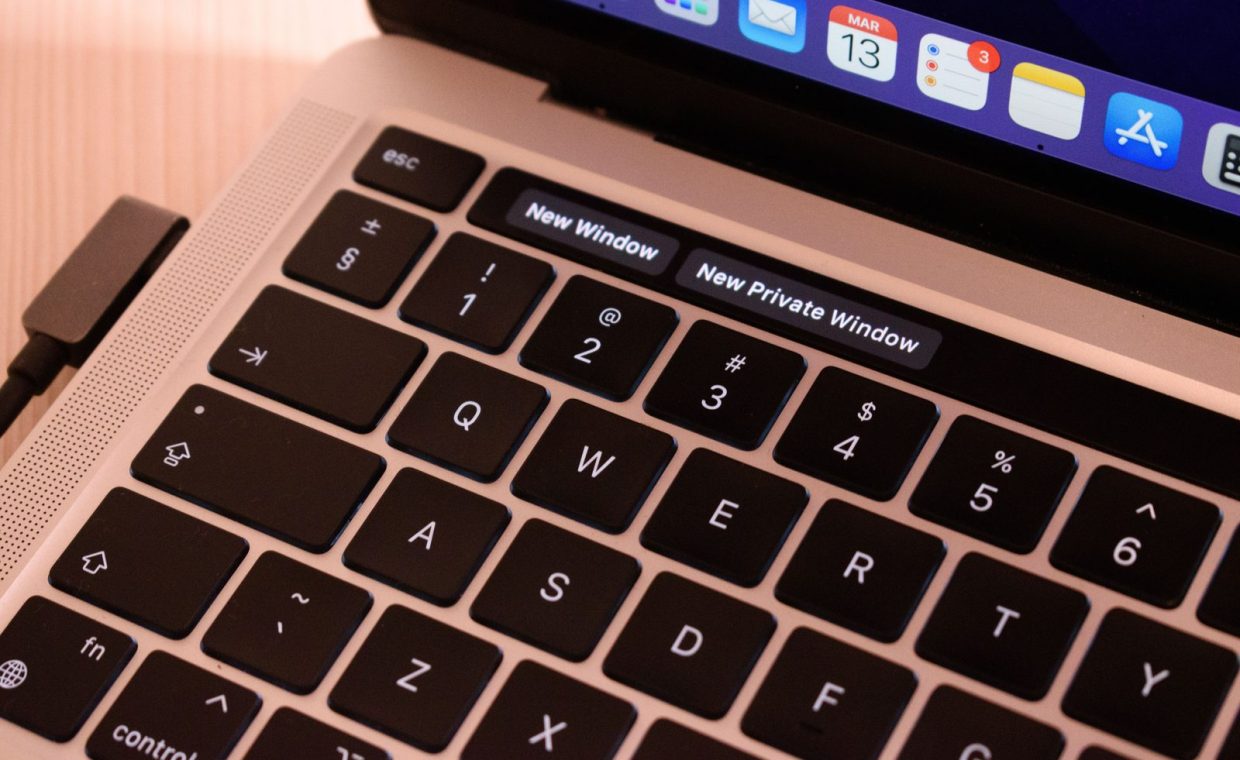 A detailed view of a laptop keyboard with browser tabs open, highlighting 'New Window' and 'New Private Window'.
