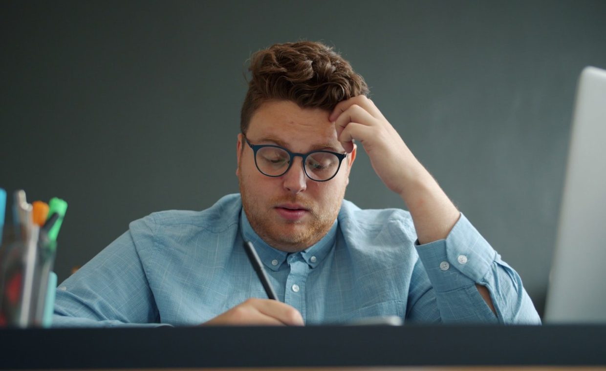 Man with glasses looking stressed at desk