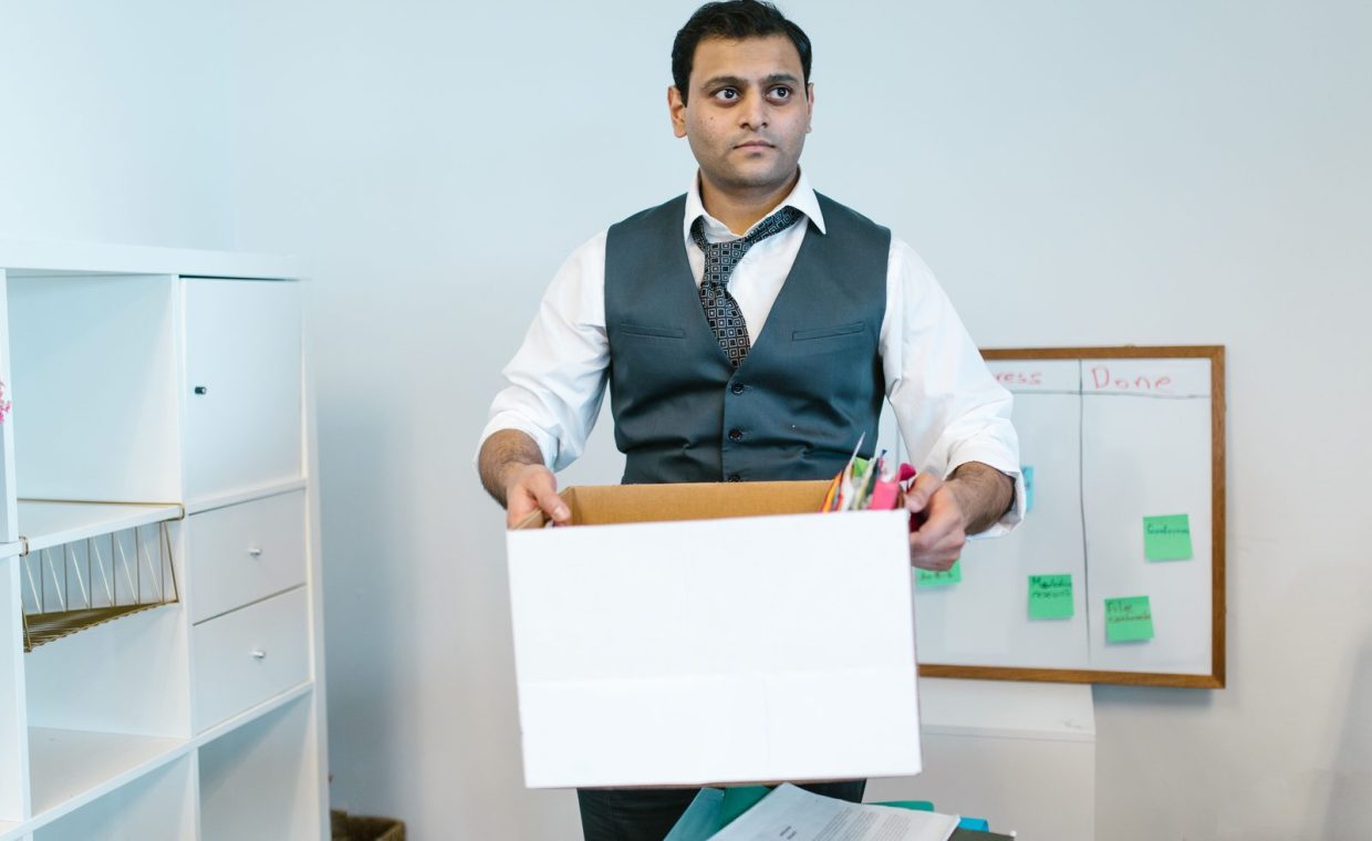 Professional man organizing office belongings in a cardboard box, preparing for transition.